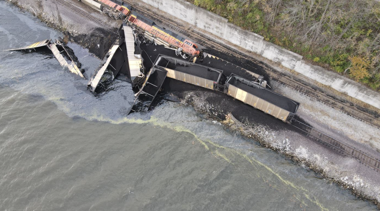 ​Aerial photo of the derailment of the two locomotives and eight hopper cars. Two additional hopper cars are submerged in the river. (Source: BNSF)​