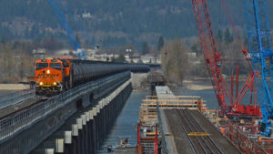 Unit crude from North Dakota to the Pacific Northwest crosses Lake Pend Oreille outside Sandpoint, Idaho, on April 29, 2023, using BNSF’s new bridge that entered service in November 2022. Workers on the older, adjacent bridge are placing concrete caps on new piers as part of a major renovation of the 119-year-old structure. (Photograph and Caption, Bruce E. Kelly)