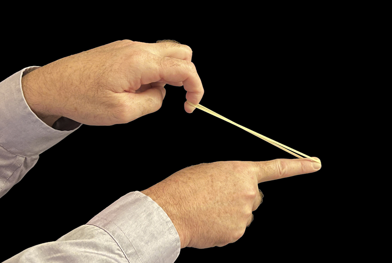 Figure 1. A stretched rubber band contains energy that we call “strain energy.” One component of strain energy is the “strain” in the band, which manifests as the band’s visible stretch. The other component of strain energy is “stress” which is invisible. (All illustrations courtesy of Gary T. Fry)