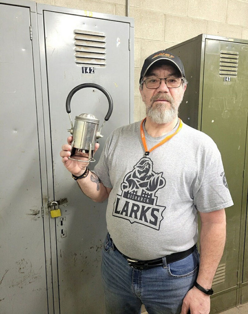 Jeff Kessel standing in front of his locker at work, holding his father’s 30-year-old carman lantern (BNSF)